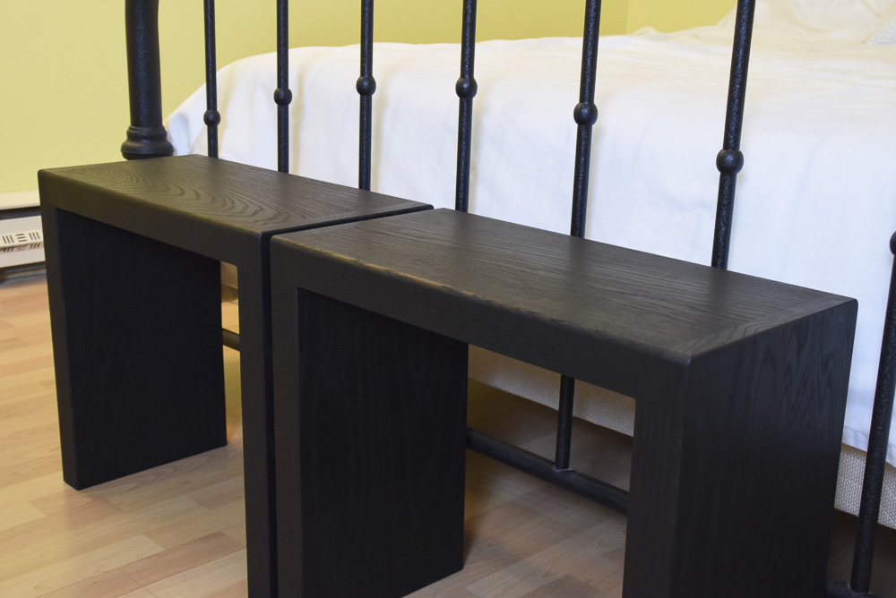 close up angled view of black oak sitting benches at end of bed