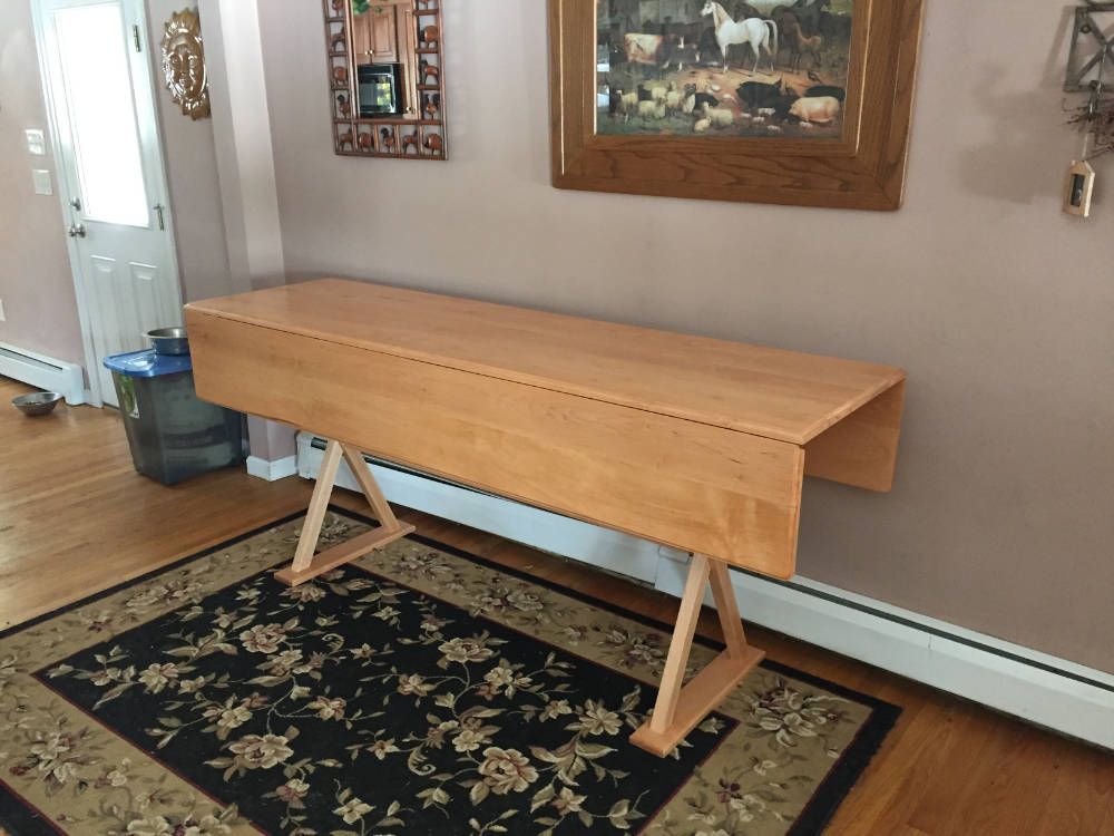 custom furniture. a light, cherry-colored, long and narrow, drop leaf console table made of maple